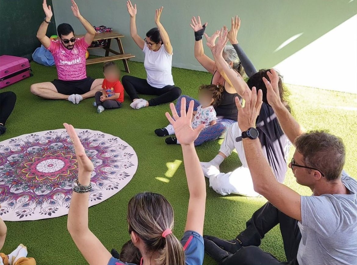 Familias con los brazos en alto durante un taller al aire libre